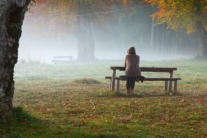 A person sitting on a park bench in the fog, representing someone searching for the right therapist