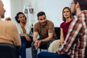 Adults sitting together talking and listening, representing a group therapy practice team