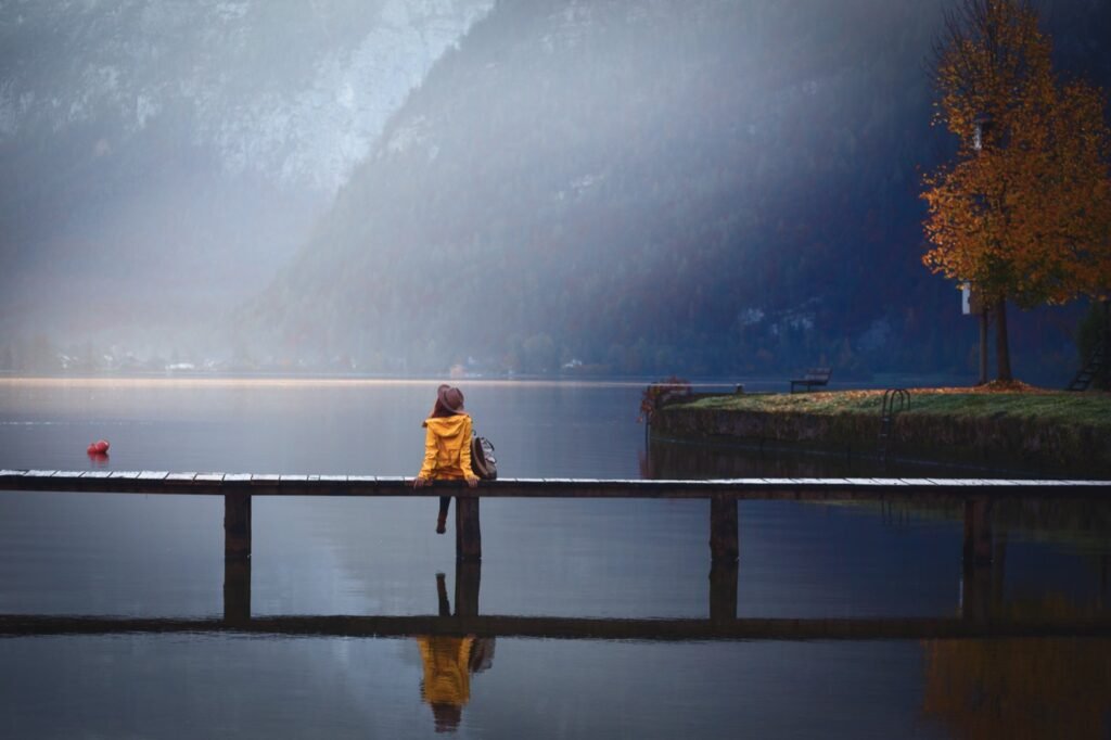 A person crossing a bridge over a mountain lake, representing the path clients take to find a therapist
