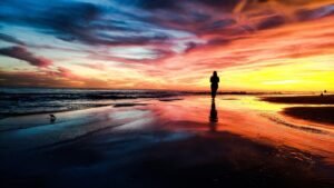 A person walking alone on a beach at sunset, representing healthy boundaries and privacy on social media